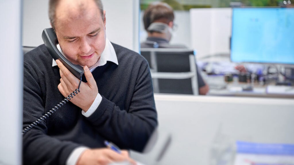Ein Mitarbeiter hält einen Telefonhörer und spricht mit einem Kunden