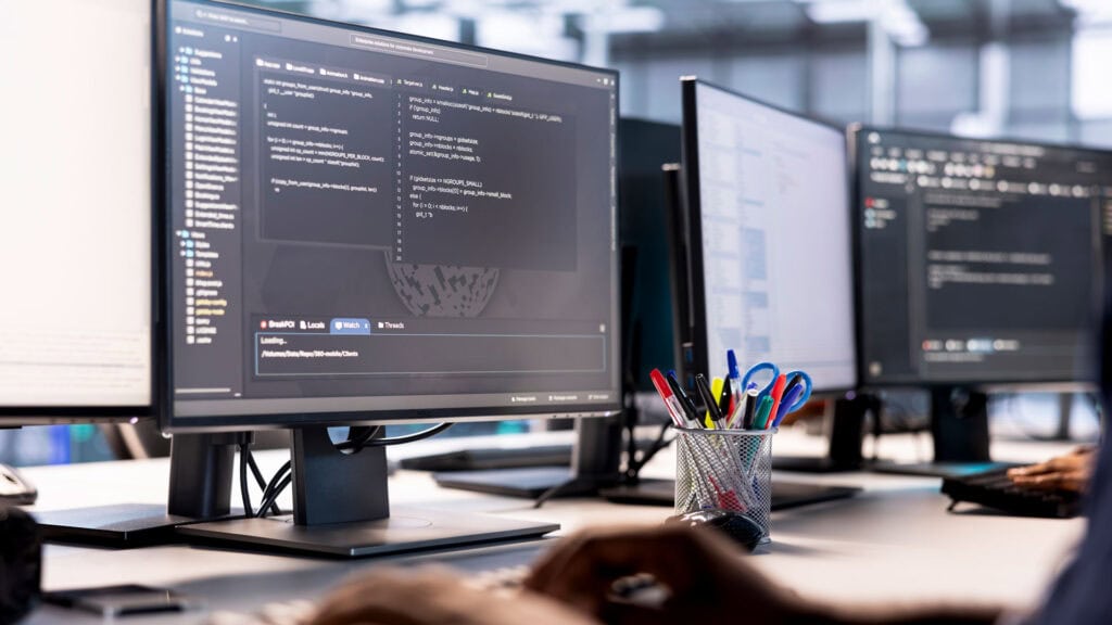 Mehrere Computer Bildschirme nebeneinander an einem Arbeitsplatz
