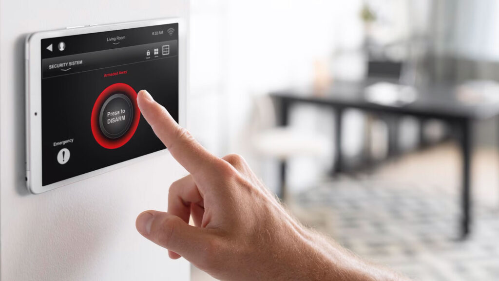 Ein Finger berührt ein Display einer an der Wand befestigten Steuerungseinheit für eine Alarmanlage
